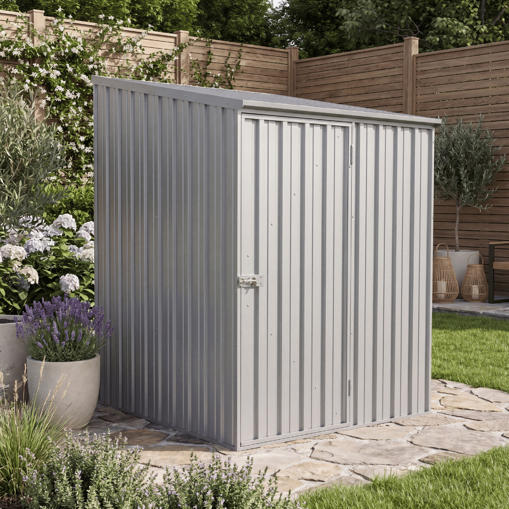 Abri de jardin métallique gris installé sur une terrasse en pierre, entouré de plantes